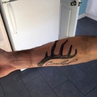 Deer horn tattoo on forearm with lettering Crooked