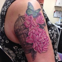 Delicate pink peony flowers, butterfly and bird cage realistic tattoo on woman's shoulder
