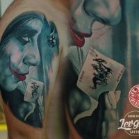 Detailed looking shoulder tattoo of Joker with playing card
