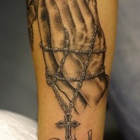 Detailed praying hands with rosary tattoo on arm