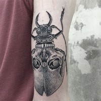 Tatuaggio di inchiostro nero a forma di punto di un grosso insetto combinato con un teschio umano