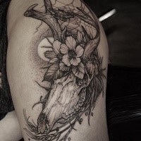 Dot style black ink thigh tattoo of large animal skull with flowers