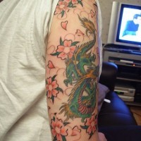 Tatuaje del dragón entre las flores de sákura en color