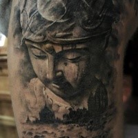 Dramatic dark colored shoulder tattoo of Buddha statue with colored lotus flower