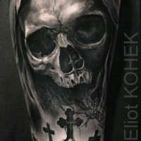 Dramatic detailed and painted by Eliot Kohek tattoo of human skull with tomb crosses