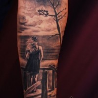 Dramatic painted black and white lonely woman on seashore tattoo on arm