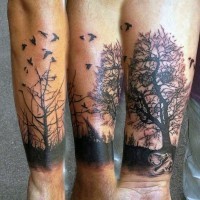 Tatuaje en el antebrazo, árboles secos y bandada de aves negras