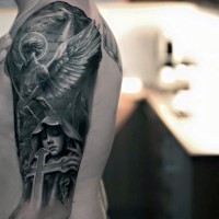 Tatuaje en el brazo, chica con cruz grande y ángel en el cielo y inscripción