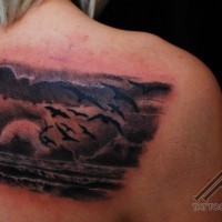 Dramatic style colored ocean shore with sun and birds tattoo on shoulder