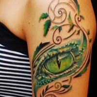Tatuaje en el brazo, ojo verde de lagarto con tallos y hojas