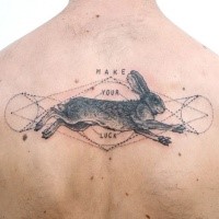 Engraving style black ink back tattoo of rabbit and lettering