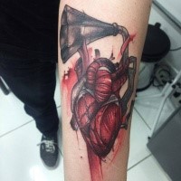 Engraving style colored forearm tattoo of human heart with gramophone
