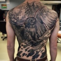 Enormous black ink whole back tattoo of detailed owl in dark forest