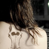 Exiting gray-ink mammoth skull tattoo on upper back