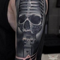 Tatuaggio fantastico progettato sul braccio superiore del cranio umano con microfono