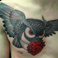 Flying owl with a red heart in its claws tattoo on chest