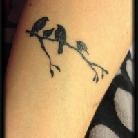 quattro piccoli uccelli neri seduti su ramo tatuaggio