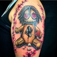 Funny 3D like colored voodoo doll tattoo on shoulder with flowers and heart