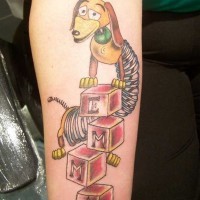 Funny cartoon hero dog toy tattoo on forearm with lettering