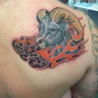 Funny cartoon like colored goat tattoo on shoulder with flames