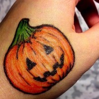 Funny colored Halloween pumpkin tattoo on hand
