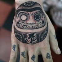 Funny illustrative style hand tattoo of daruma doll with lettering