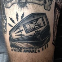 Funny little black ink coffin with sand clock, lettering and skeleton hand tattoo on thigh