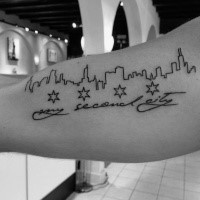 Funny looking black ink city shaped arm tattoo with lettering