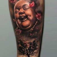Funny looking colored forearm tattoo of Buddha statue and blooming tree