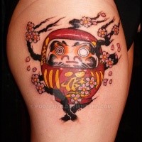 Funny looking colored thigh tattoo of daruma doll with blooming tree