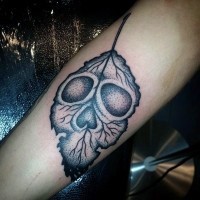 Tatuaje en el antebrazo, hoja decorada con cráneo, colores negro blanco