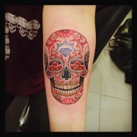 Funny smiling multicolored skull in Mexican style forearm tattoo