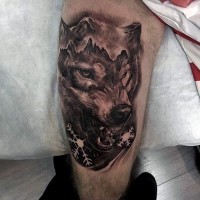 Tatuaje en el muslo,  lobo combinado con montañas y copas de nieve