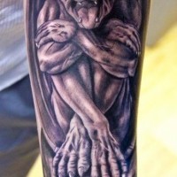 Gargoyle sitting on skull forearm tattoo