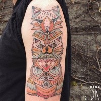 Geometrical style colored upper arm tattoo of old totem