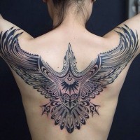 Giant dark black ink flying bird tattoo on back in tribal style