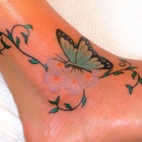 Tatuaje en el pie, mariposa linda en flores suaves