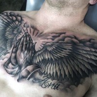 Gorgeous black and white religious themed tattoo with praying hands and wings on chest