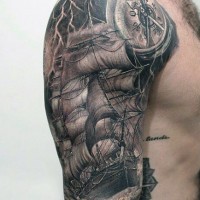 Gorgeous black and white very realistic tattoo on shoulder with sailing ship on storming sea