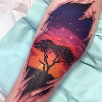 mozzafiato colorato albero solitario  su tramonto tatuaggio su gamba