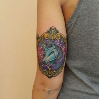 Tatuaje multicolor en el brazo, unicornio fantástico en el marco antiguo