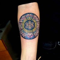 Gorgeous painted and colored circle shaped tattoo on forearm stylized with flowers