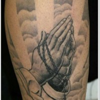 Tatuaje en el brazo, manos que oran en el cielo