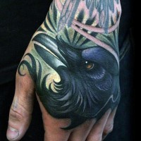 Gorgeous painted realistic colorful crow tattoo on hand