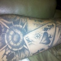 Graues Tattoo von einer Spielkarte mit Pistole und Gewehrschußverletzung als Ärmel gestaltet am Unterarm