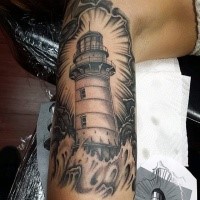 Gray washed style colored arm tattoo of lighthouse and waves