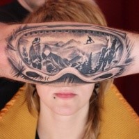 Gray washed style colored arm tattoo of snowboarders mask
