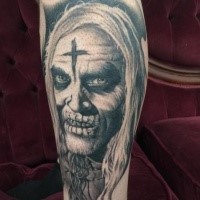 Gray washed style colored leg tattoo of creepy human face with cross