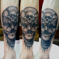 Gray washed style detailed forearm tattoo of human skull stylized with smaller skull