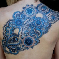 Great blue colored floral tattoo stylized with different ornaments on upper back